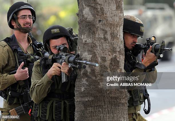 Israeli soldiers aim at Palestinian protesters during clashes following a protest marking Land Day on March 30, 2015 in the West Bank village of...