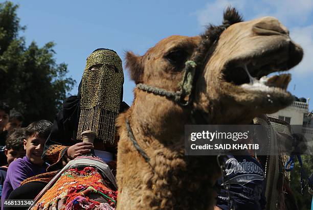 Palestinian children get on camels during activities organised to mark Land Day in Rafah, in the southern Gaza Strip, on March 30, 2015. On the...
