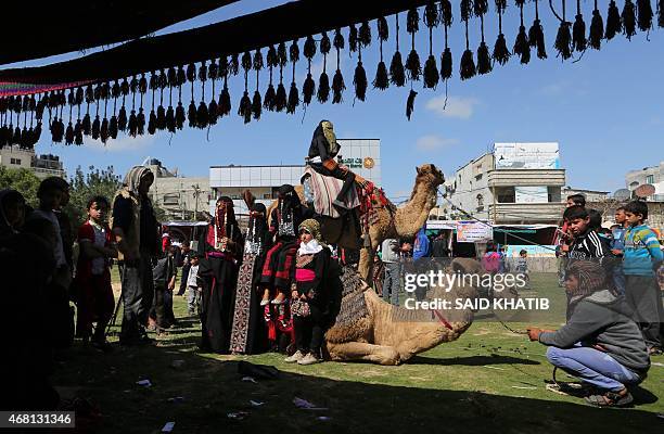 Palestinians get on camels during activities organised to mark Land Day in Rafah, in the southern Gaza Strip, on March 30, 2015. On the annual Land...