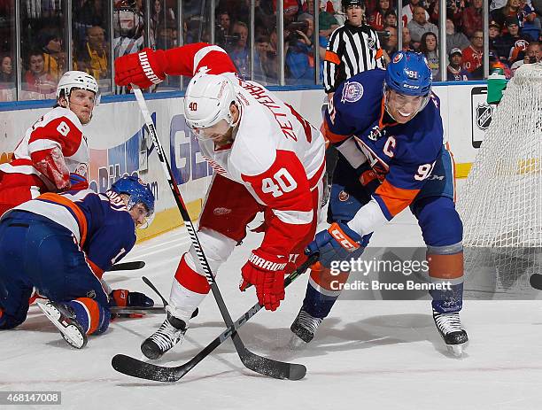 John Tavares of the New York Islanders trips up Henrik Zetterberg of the Detroit Red Wings at the Nassau Veterans Memorial Coliseum on March 29, 2015...