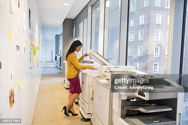 full length of businesswoman using photocopier - by the photocopier stockfoto's en -beelden