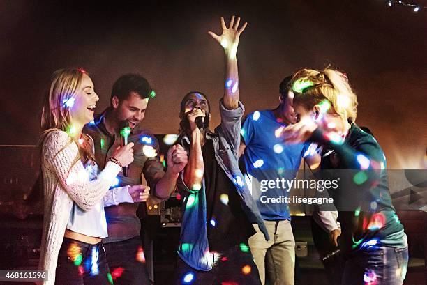 grupo de amigos haciendo karaoke - clubs fotografías e imágenes de stock