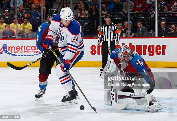 Matt Fraser of the Edmonton Oilers controls the puck against Tyson Barrie of the Colorado Avalanche and looks to get off a shot against goalie Semyon...