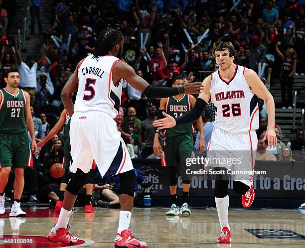 DeMarre Carroll high fives teammate Kyle Korver of the Atlanta Hawks during the game against the Milwaukee Bucks on March 30, 2015 at Philips Arena...