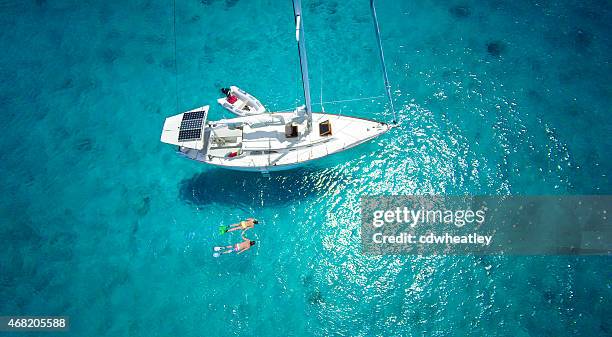 luftbild von paar schnorcheln neben einem luxus-segelboote - karibik stock-fotos und bilder