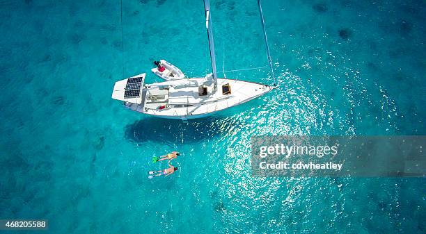 vista aérea de pareja haciendo esnórquel junto a un velero de lujo - vela parte del barco fotografías e imágenes de stock