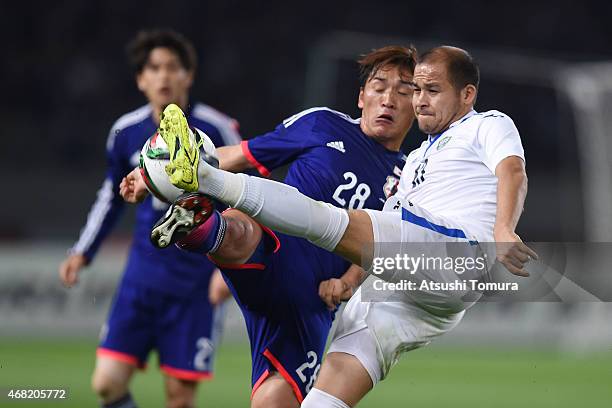 Toshihiro Aoyama of Japan and Lutfulla Turaev of Uzbekistan compete for the ball during the international friendly match between Japan and Uzbekistan...