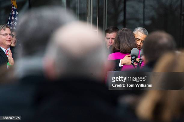 President Barack Obama hugs Victoria Reggie Kennedy, as Edward Kennedy Jr., far left, looks on, during a dedication ceremony for the Edward M....