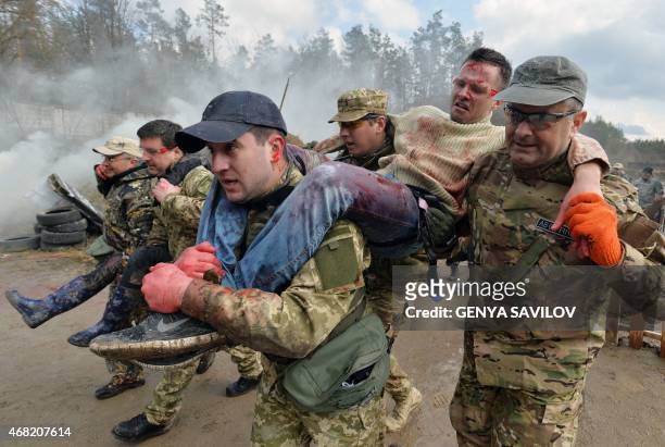 Participants reinact a war situation during a training session on a shooting range outside Kiev on March 31, 2015. First aid students including Kiev...