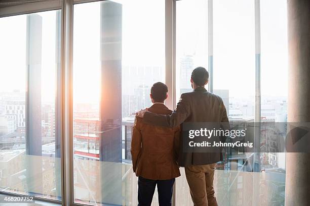 two men admiring city through window - arms around stock pictures, royalty-free photos & images