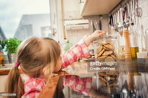 kleines mädchen mit hafer cookies von einem gefäß - child cookie jar stock-fotos und bilder
