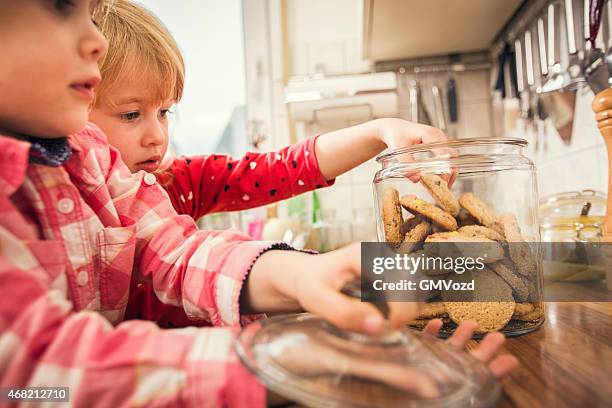 kleines mädchen mit hafer cookies aus einem krug - child cookie jar stock-fotos und bilder