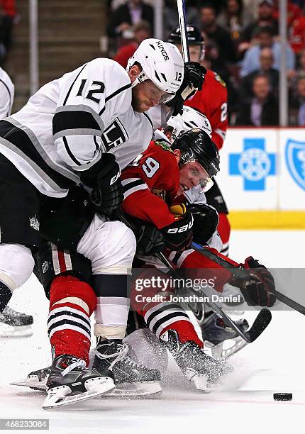 Jonathan Toews of the Chicago Blackhawks tries to get off a shot as he's squeezed by Marian Gaborik and Jake Muzzin of the Los Angeles Kings at the...