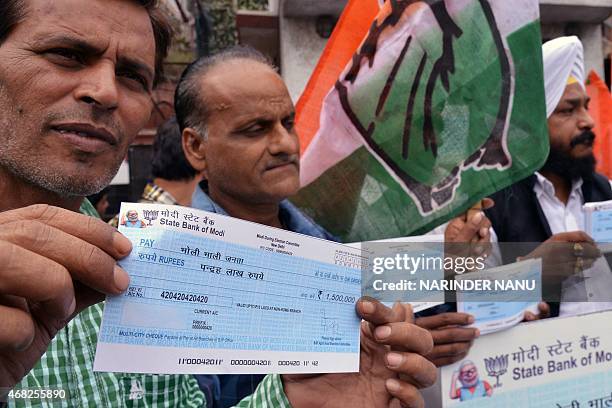 Congress Party activists hold up dummy cheques during a protest against Indian Prime Minister Narendra Modi in Amritsar on April 1, 2015. Protesters...