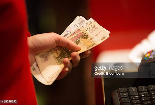 An employee holds ruble banknotes at the payment counter inside the new Hamleys Plc toy store on its opening day in Moscow, Russia, on Tuesday, March...