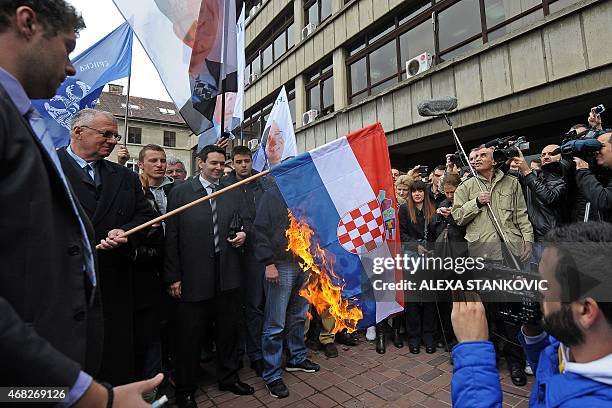 Serbian nationalist politician Vojislav Seselj surrounded by his supporters burns a Croatian flag on April 1, 2015 outside a tribunal in Belgrade....