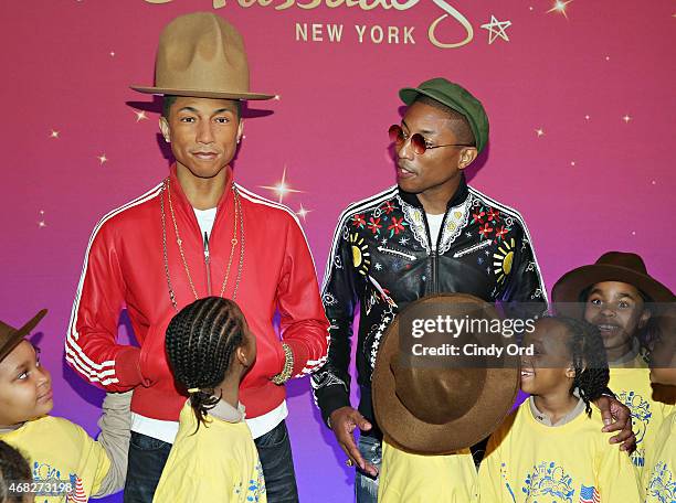 Recording artist Pharrell Williams poses with youth from Madame Tussauds' parent company Merlin Entertainments 'Merlin's Magic Wand' after he...