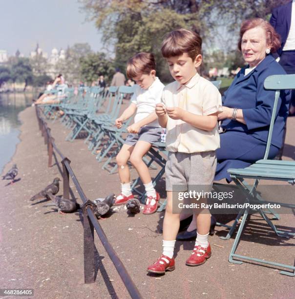 John F Kennedy Junior , son of the late United States president, and his cousin Anthony Radziwill feeding the pigeons in St James' Park while touring...