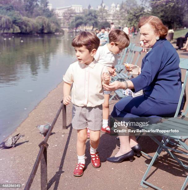John F Kennedy Junior, son of the late United States president and his cousin Anthony Radziwill, feeding pigeons in St James' Park while touring...