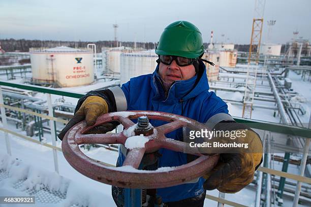 An employee adjusts a valve wheel at the central processing plant for oil and gas at the Salym Petroleum Development oil fields near the Bazhenov...