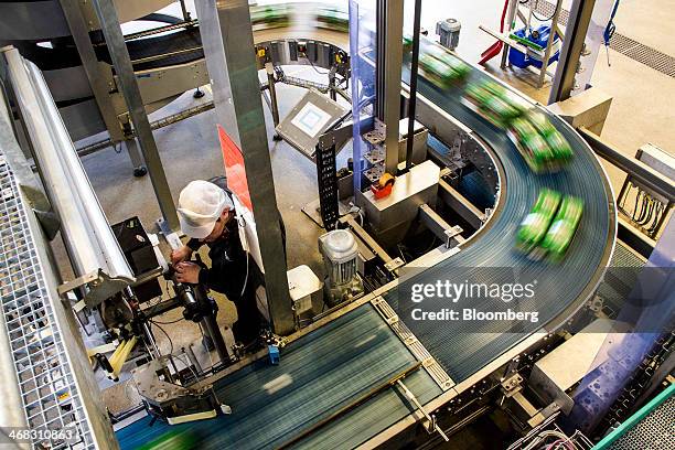 An employee watches a labelling machine as six packs of Tuborg Classic beer move along the production line at the Carlsberg A/S brewery in...