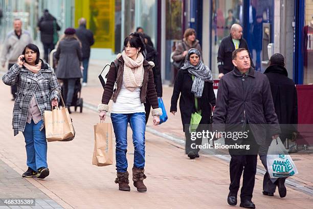 Pedestrians carry Primark and Poundland branded shopping bags as they pass stores in Croydon, south London, U.K., on Monday, Feb. 10, 2014. Westfield...