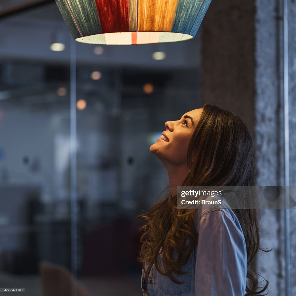 Young happy woman looking at lamp.