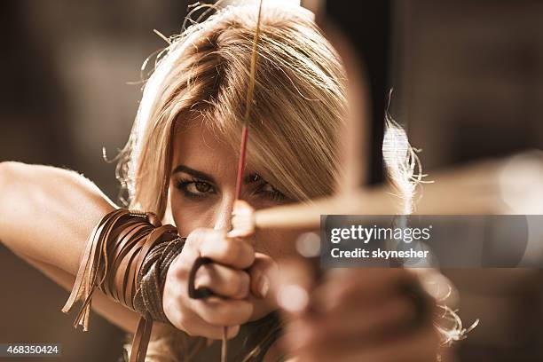 woman archer aiming with bow and arrow. - arrow bow and arrow stockfoto's en -beelden