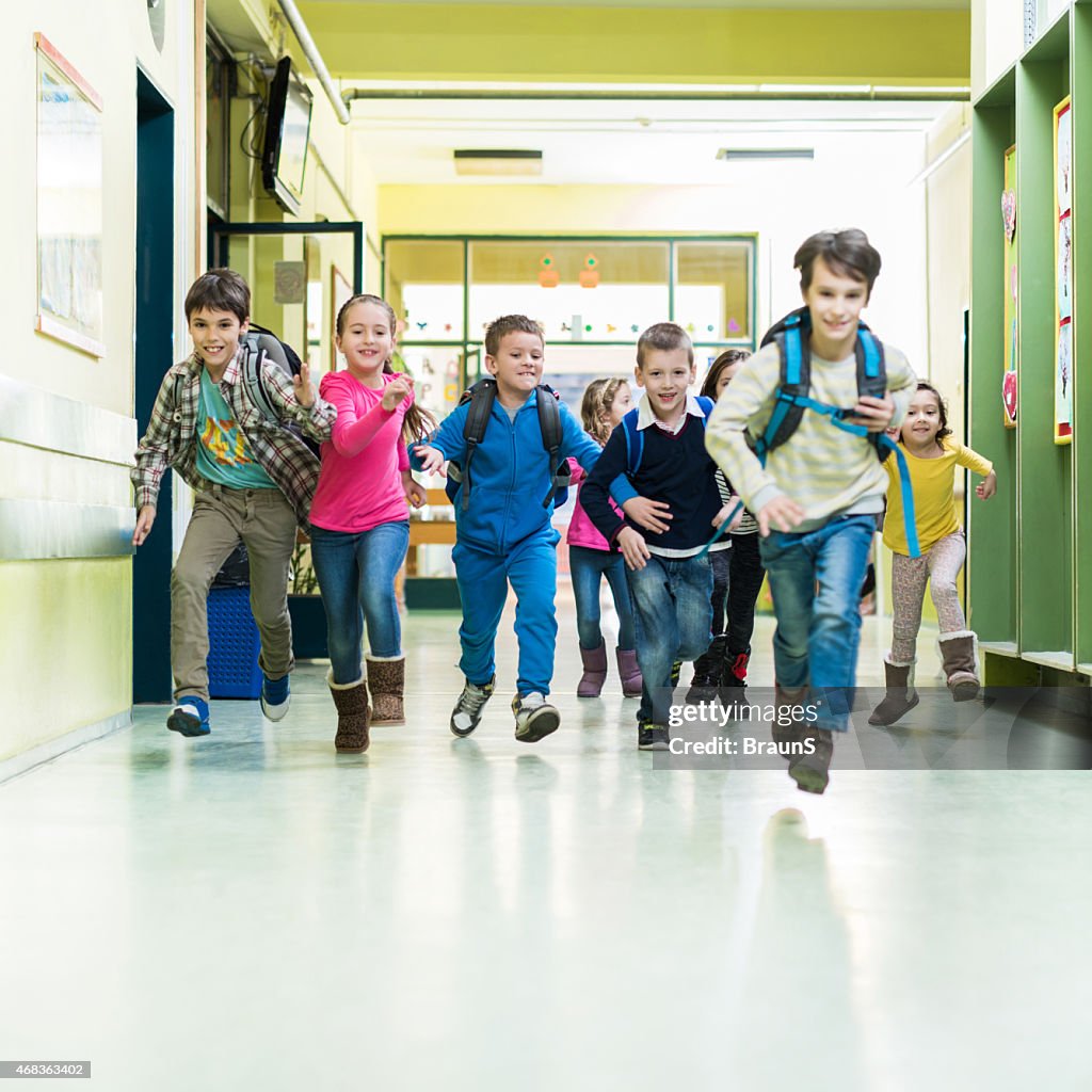 Large group of school children running in the hall.