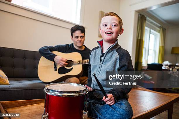 cute boy with down syndrome playing music with dad. - music therapy stock pictures, royalty-free photos & images