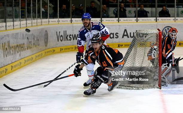 Tim Hambly of Wolfsburg and Jonathan Rheault of Mannheim battle for the puck in game four of the DEL semi final play-offs between Grizzly Adams...