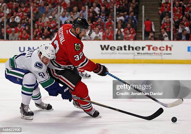 Michal Rozsival of the Chicago Blackhawks is pressured by Derek Dorsett of the Vancouver Canucks at the United Center on April 2, 2015 in Chicago,...