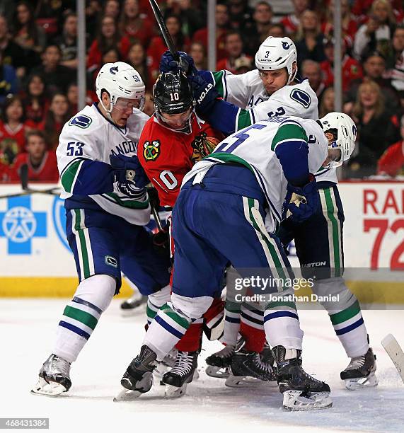 Patrick Sharp of the Chicago Blackhawks is defended by Bo Horvat, Kevin Bieksa and Luca Sbisa of the Vancouver Canucks at the United Center on April...