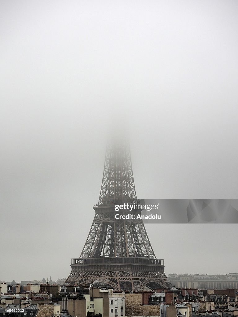 Eiffel Tower partially covered by fog