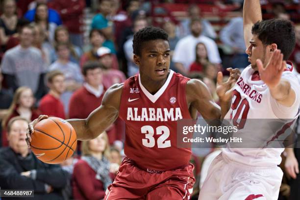 Retin Obasohan of the Alabama Crimson Tide drives to the middle against Kikko Haydar of the Arkansas Razorbacks at Bud Walton Arena on February 5,...