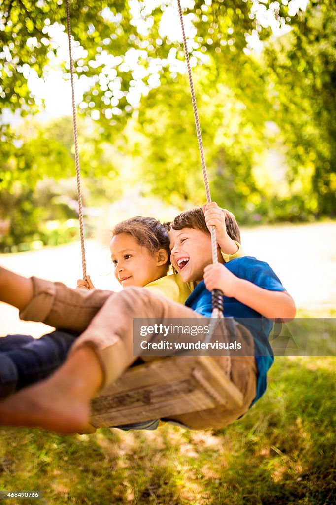 Girl and boy having fun as team to swing high