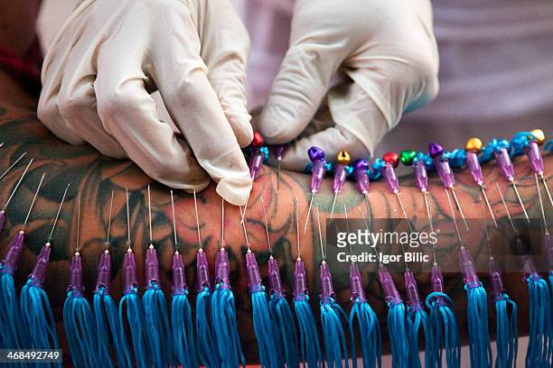 Thai man getting his tattoed arm pierced with syringe needles at Jui Tui Chinese shrine in Phuket Town. The Phuket Vegetarian Festival is an annual...