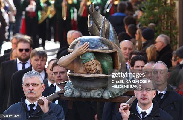 Members of craftsmen guilds carry a statue of Jonah and the Whale during a Good Friday procession on April 3, 2015 in Lohr am Main, southern Germany....