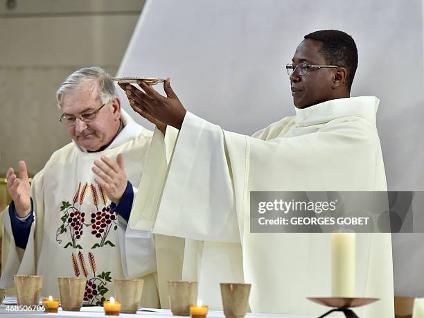 Beninese father Aubin Legodjou and another priest celebrate the Holy Thursday Chrism Mass on April 2, 2015 at the church of Sainte Therese in La...