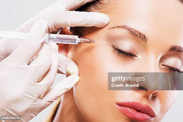 frau mit ihren augen geschlossen erhalt von botox-spritze. - gesichtstraffung stock-fotos und bilder