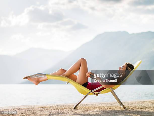 seitenansicht einer frau entspannung im liegestuhl. - beach deck chairs stock-fotos und bilder