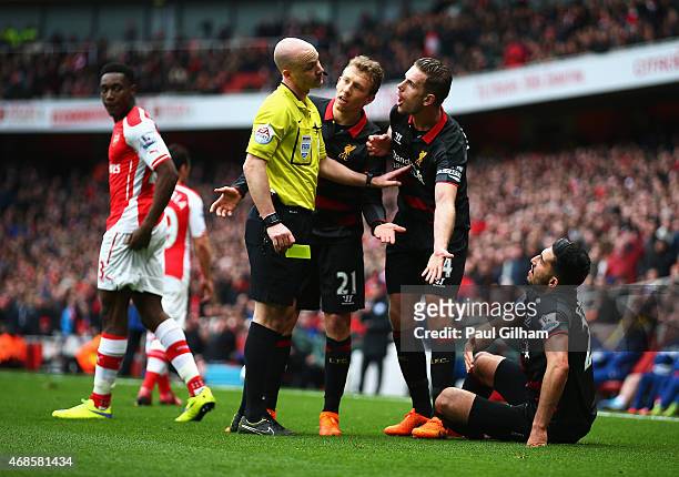 Jordan Henderson of Liverpool and Lucas Leiva of Liverpool argue with referee Anthony Taylor as Emre Can of Liverpool sits on the turf during the...