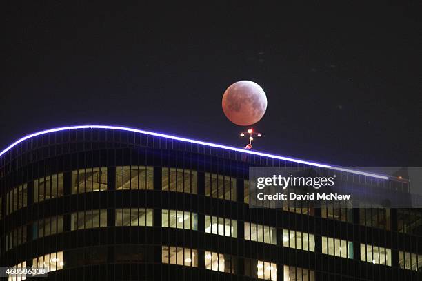 The moon is seen behind downtown high-rise buildings during the shortest total lunar eclipse of the century before dawn on April 4, 2014 in Los...