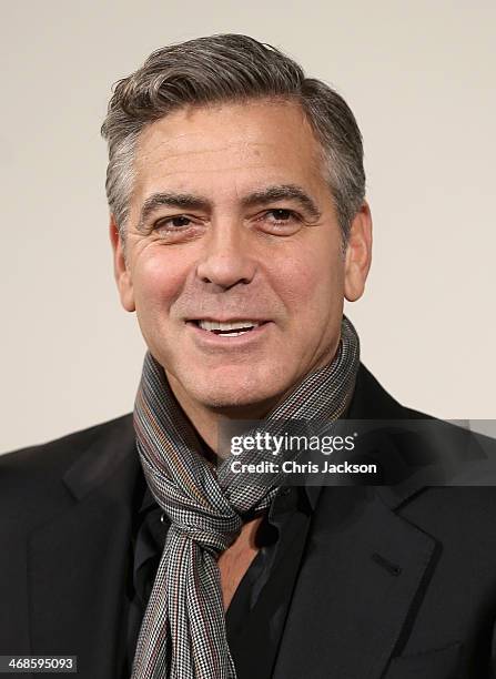 Actor George Clooney poses in fron of the painting 'Cupid Complaining to Venus' by Lucas Cranach the Elder as he attends a photocall for "The...