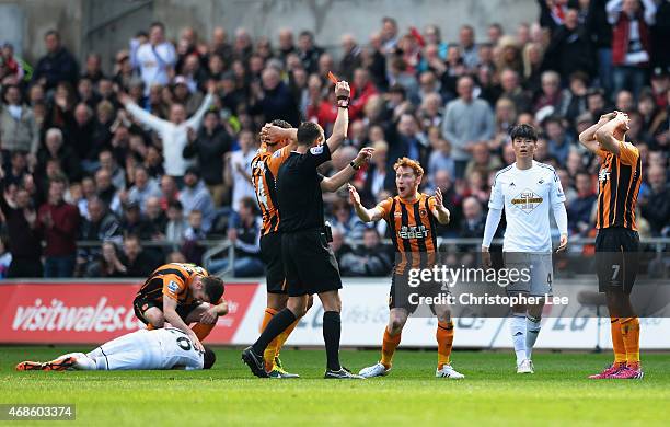 Referee Andre Marriner shows the red card to David Meyler of Hull City during the Barclays Premier League match between Swansea City and Hull City at...
