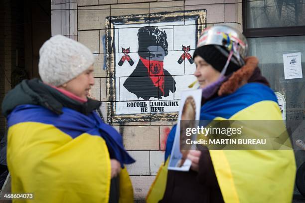 An anti-government protester holds a picture of jailed former Ukrainian Prime minister Yulia Tymoshenko as she speaks with another protester in front...