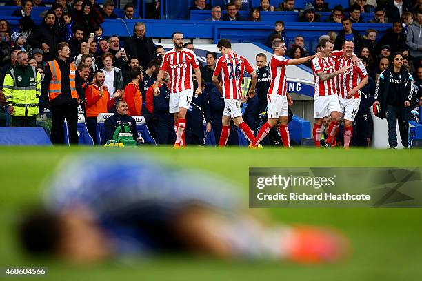 Charlie Adam of Stoke City celebrates with team-mates after scoring his team's first goal as Eden Hazard of Chelsea lies on the floor during the...