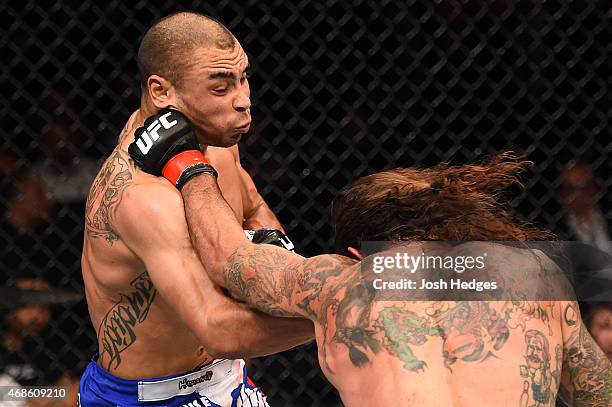 Clay Guida punches Robbie Peralta in their featherweight fight during the UFC Fight Night event at the Patriot Center on April 4, 2015 in Fairfax,...
