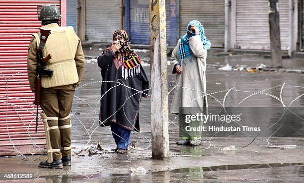 Policeman stop Kashmiri women near barbed wire duringduring Third consecutive day Curfew-like restrictions on February 11, 2014 in Srinagar, India....