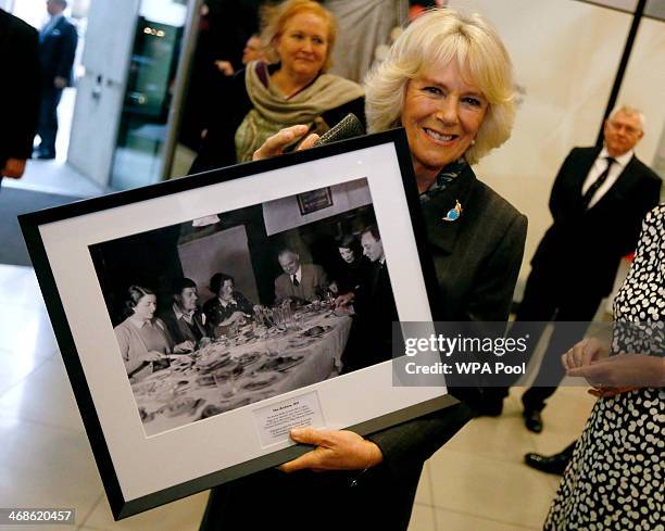 Camilla, Duchess of Cornwall poses with a picture of the original "Archers" radio soap cast given to her during a visit to the British Broadcasting...